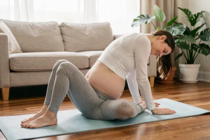 Femme enceinte pratiquant un étirement doux de yoga sur un tapis bleu pour soulager les douleurs lombaires